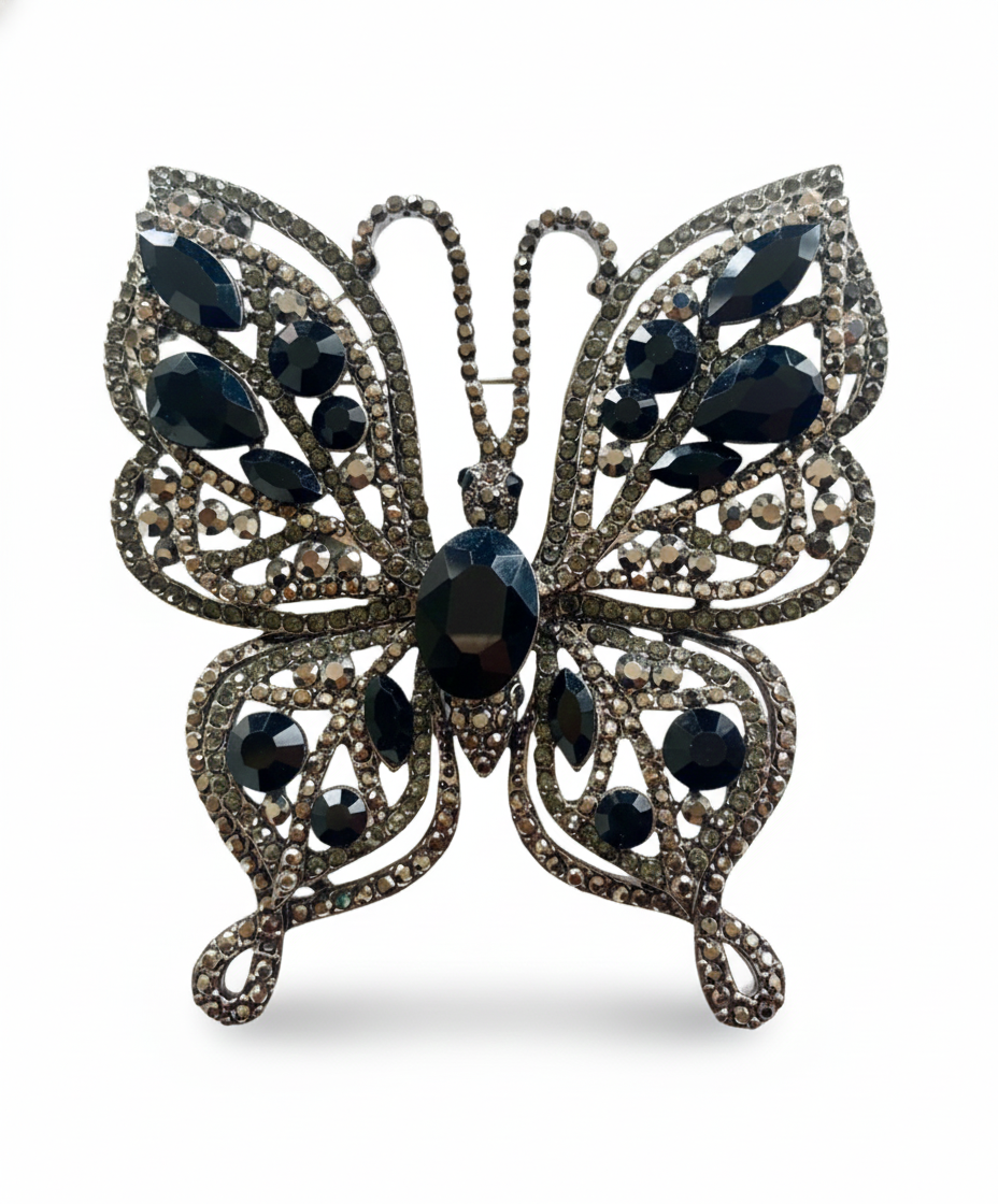 Butterfly-shaped brooch with black gemstones on a white background