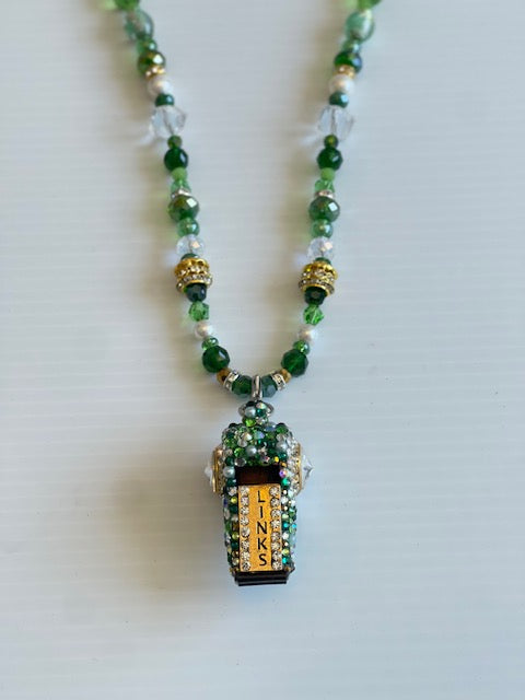 Necklace with green beads and a decorative pendant on a white background