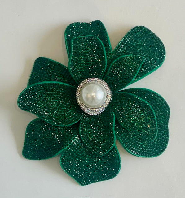 Green flower-shaped brooch with a pearl center on a white background