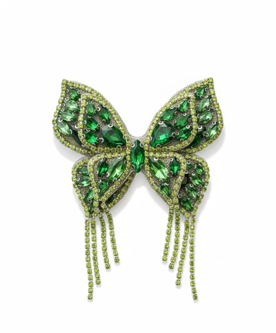 Green butterfly-shaped brooch with gemstones on a white background