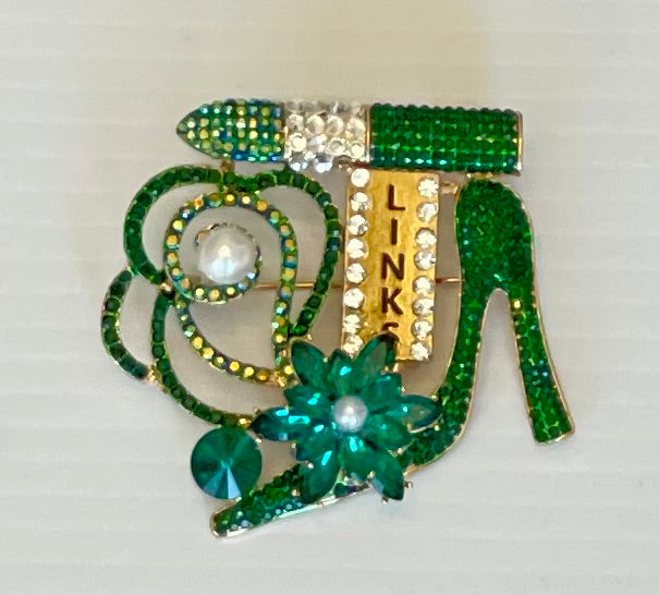 Green jeweled shoe brooch with 'LINKS' text on a white background
