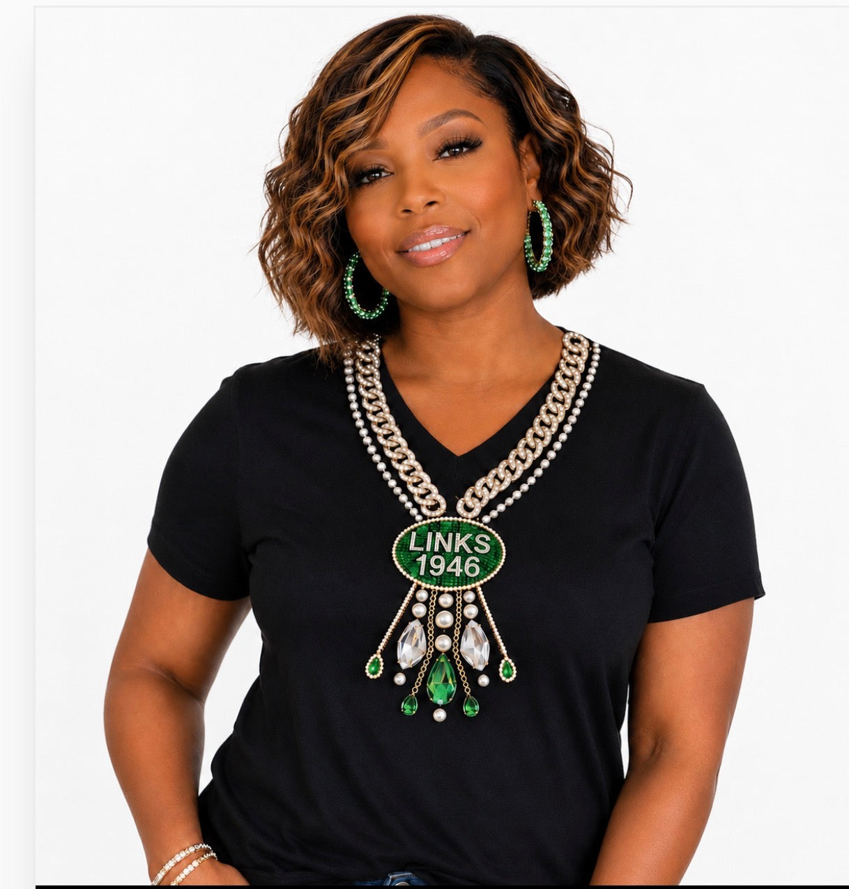 Woman wearing a black t-shirt with a decorative necklace and green earrings on a white background
