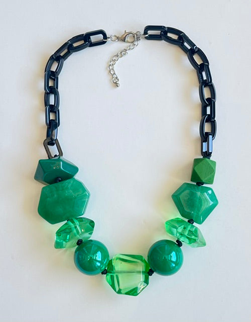 Necklace with green beads and black chain on a white background