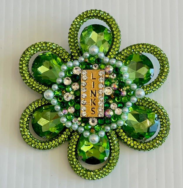 Green shamrock brooch with 'LINKS' charm on a white background